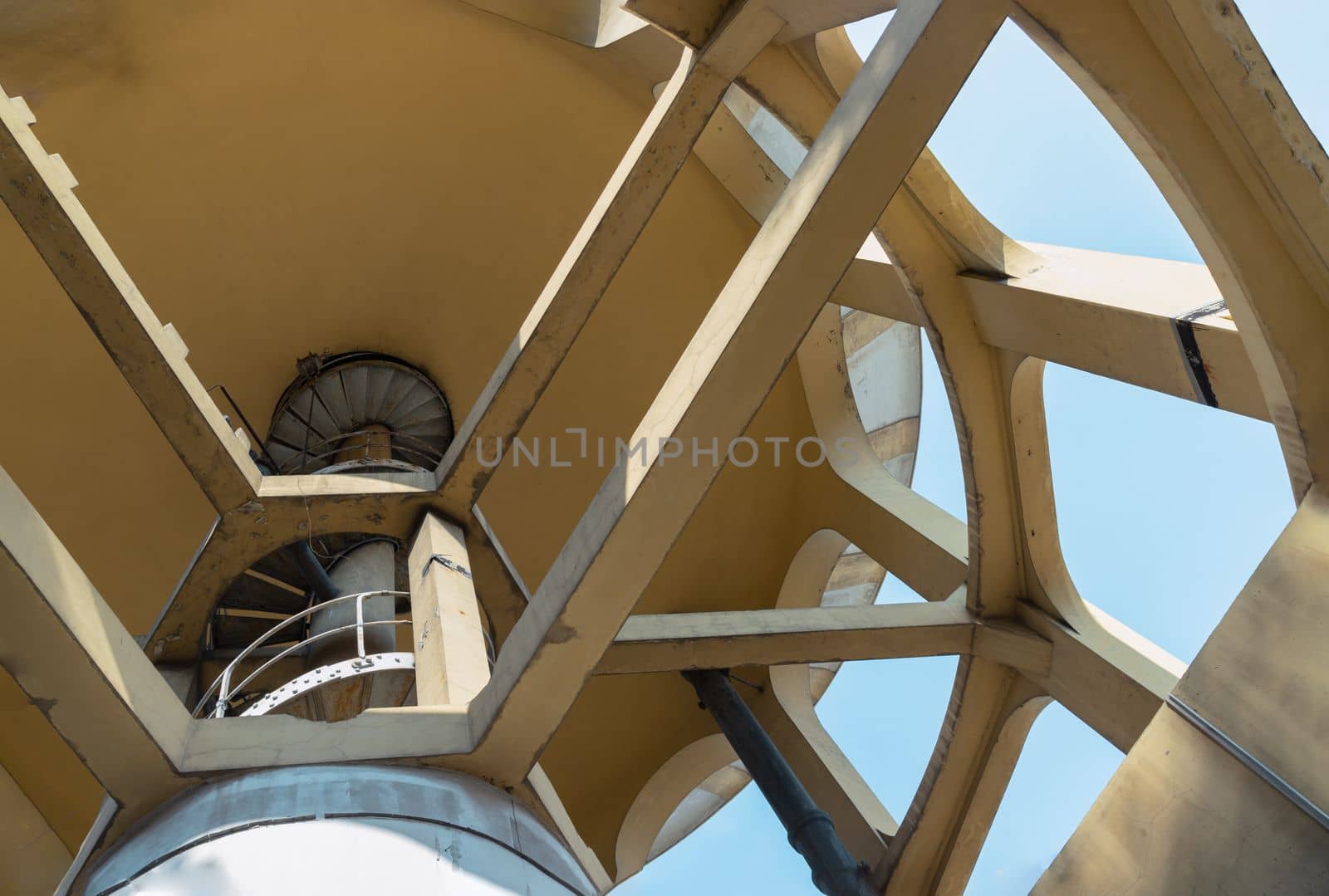 Bangkok, Thailand - 09 Feb, 2023 - A bottom-up view of columnar structures old water tower made of cement and metal spiral staircase. Large water tank in the water supply system. Selective focus.
