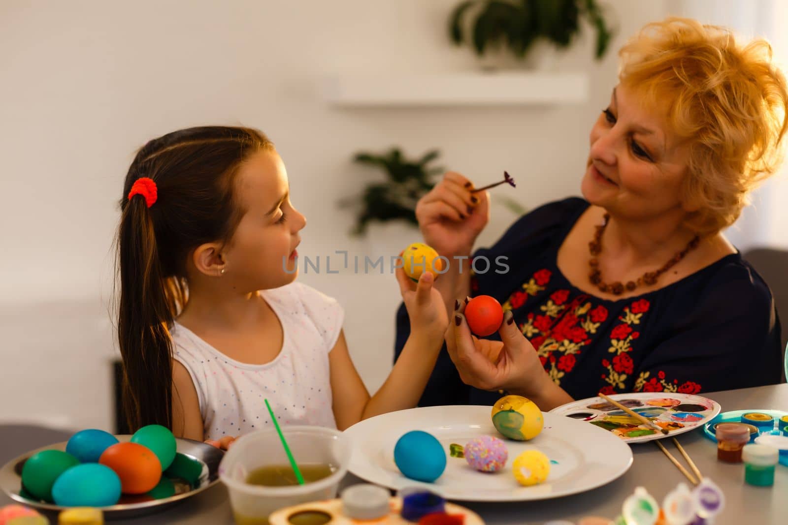 Grandmother with granddaughter are coloring eggs for Easter. by Andelov13