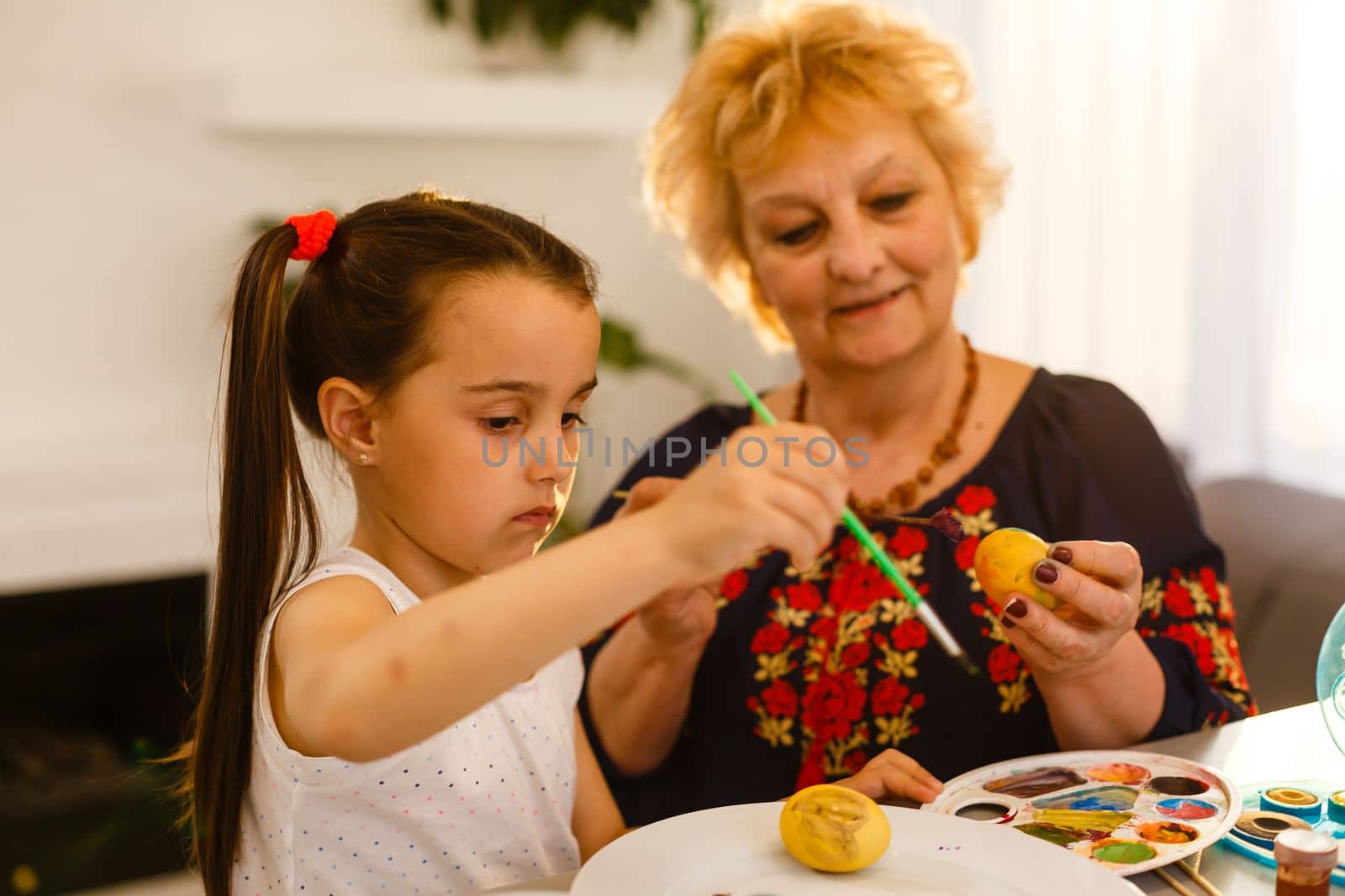 grandmother with granddaughter play with easter eggs, easter time to paint eggs