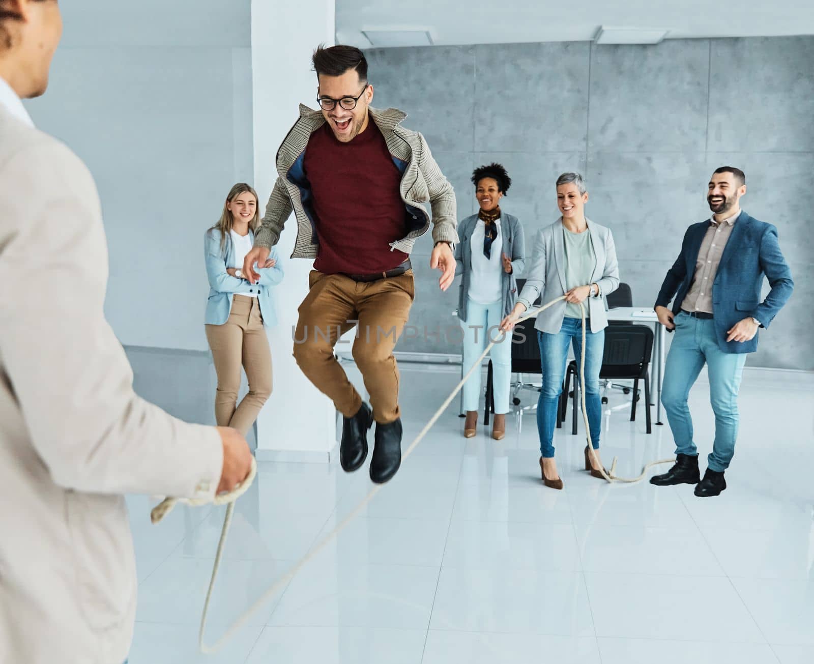 Portrait of a group of young business people having fun jumping rope during a meeting in the office. Teamwork and success concept