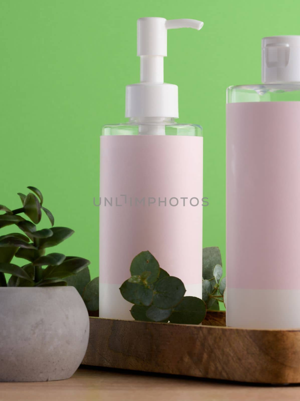 Bottles for cosmetics with a pink paper label on a green background. Bottle for tonic, gel