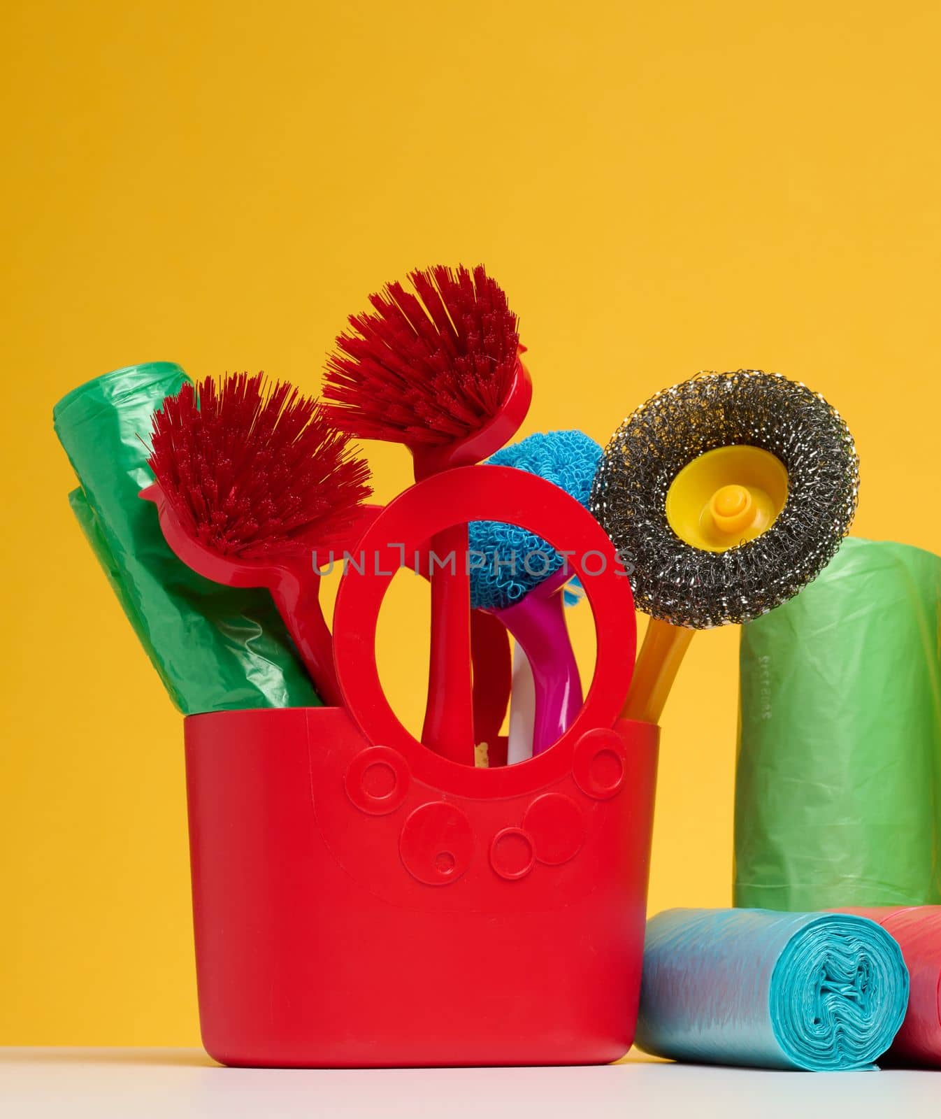 Plastic basket with brushes, disinfectant in a bottle on a yellow background. by ndanko