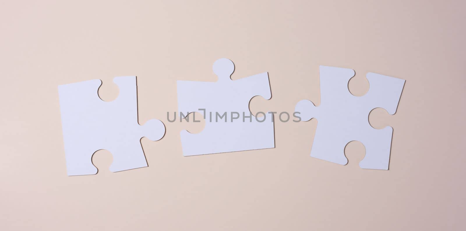 Empty white big puzzles on a beige background. Concept in business, flat lay