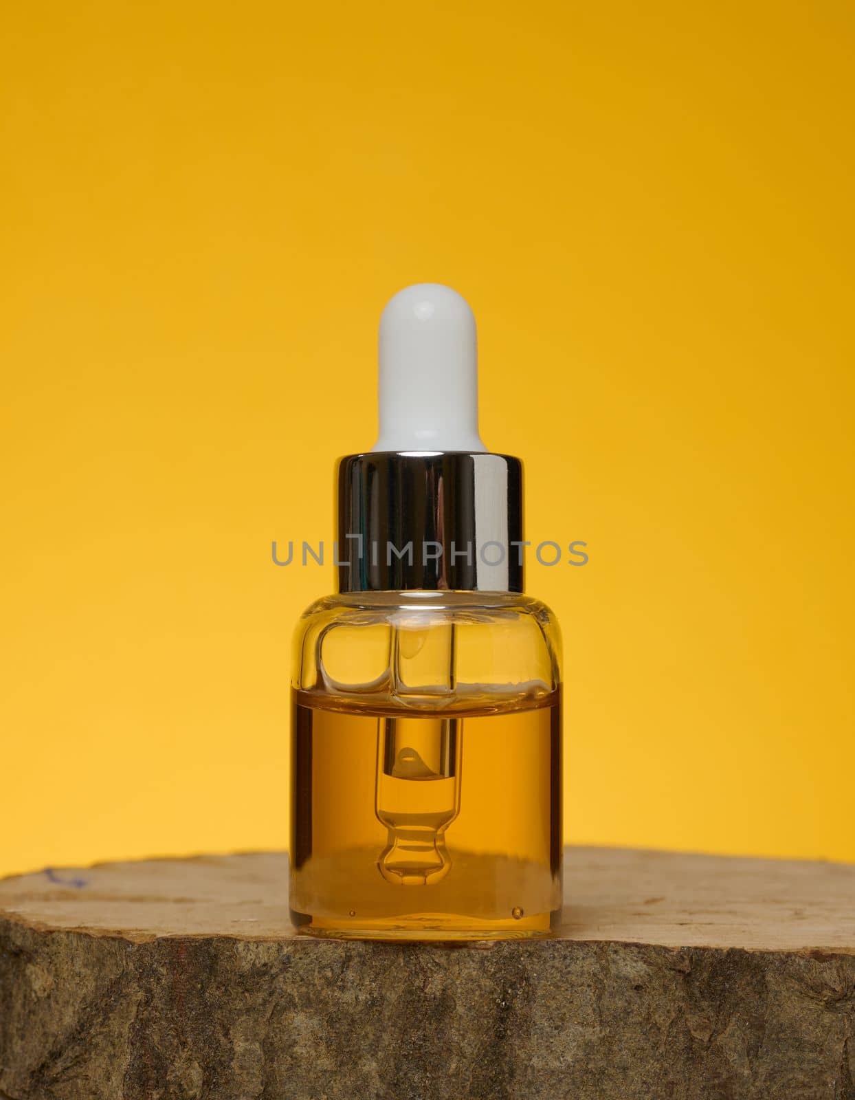 Glass transparent bottle with pipette and yellow oil. Containers for acids, cosmetics by ndanko