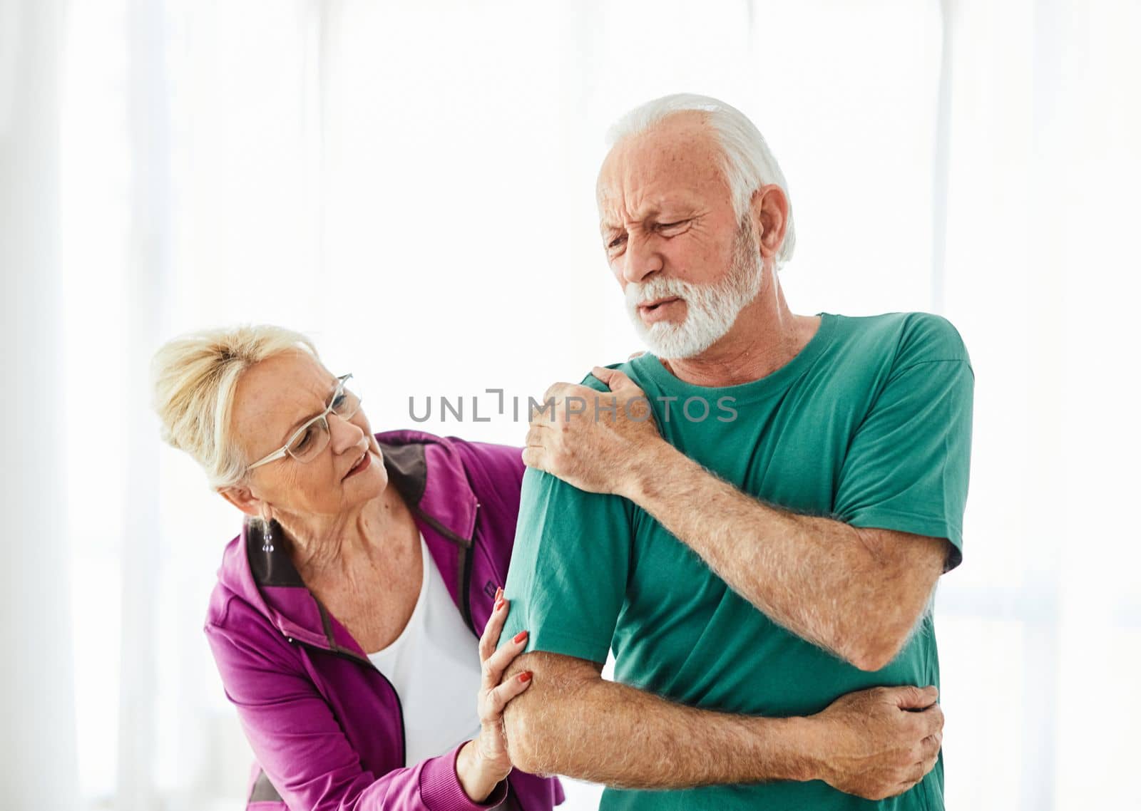 Senior couple exercising at home, suffering a shoulder injury pain health care