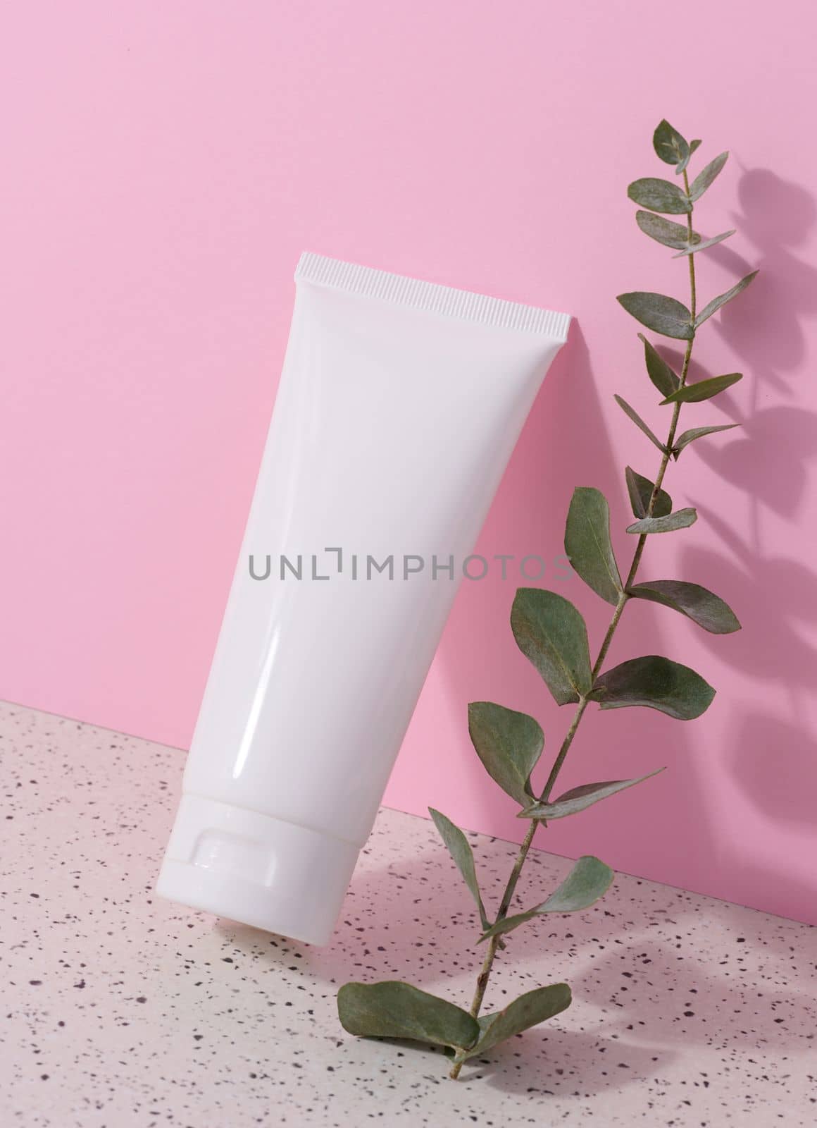 White plastic tube for liquid cosmetics on a pink background, packaging by ndanko