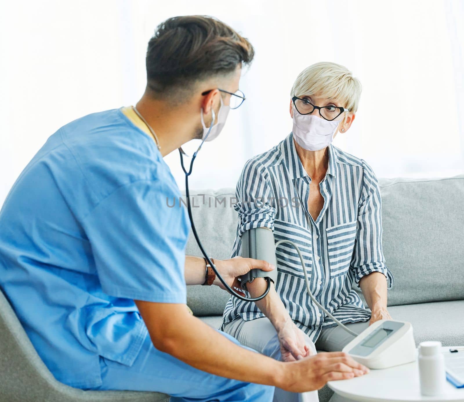 Doctor or nurse caregiver with senior woman wearing protective masksat home or nursing home
