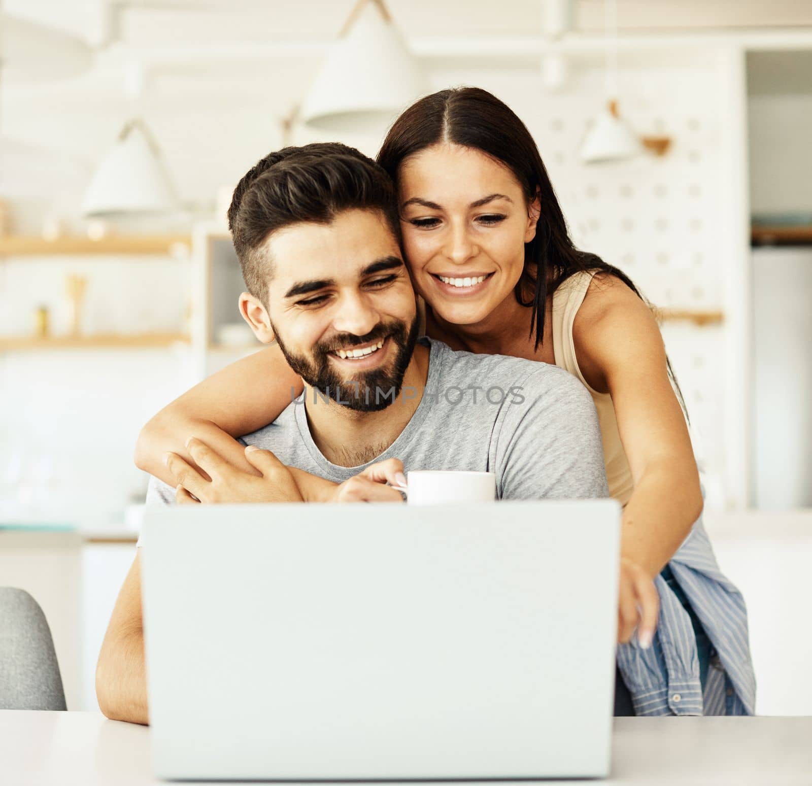 Portrait of a young happy smiling couple using laptop together at home. Wireless technology computer concept