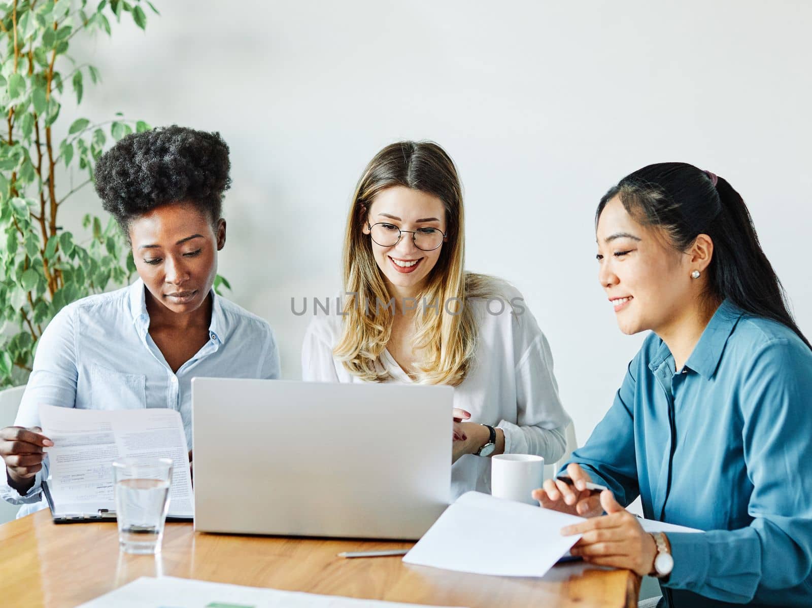 Portrait of a group of young businesswomen multiethnic working with laptop on desk and talking in a start up office