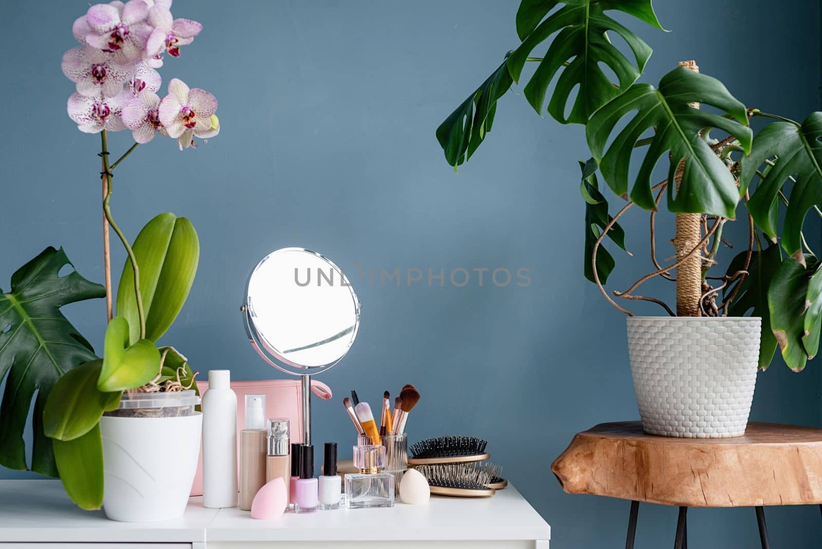 Stylish light room interior with elegant vanity table and plants, beauty and fashion