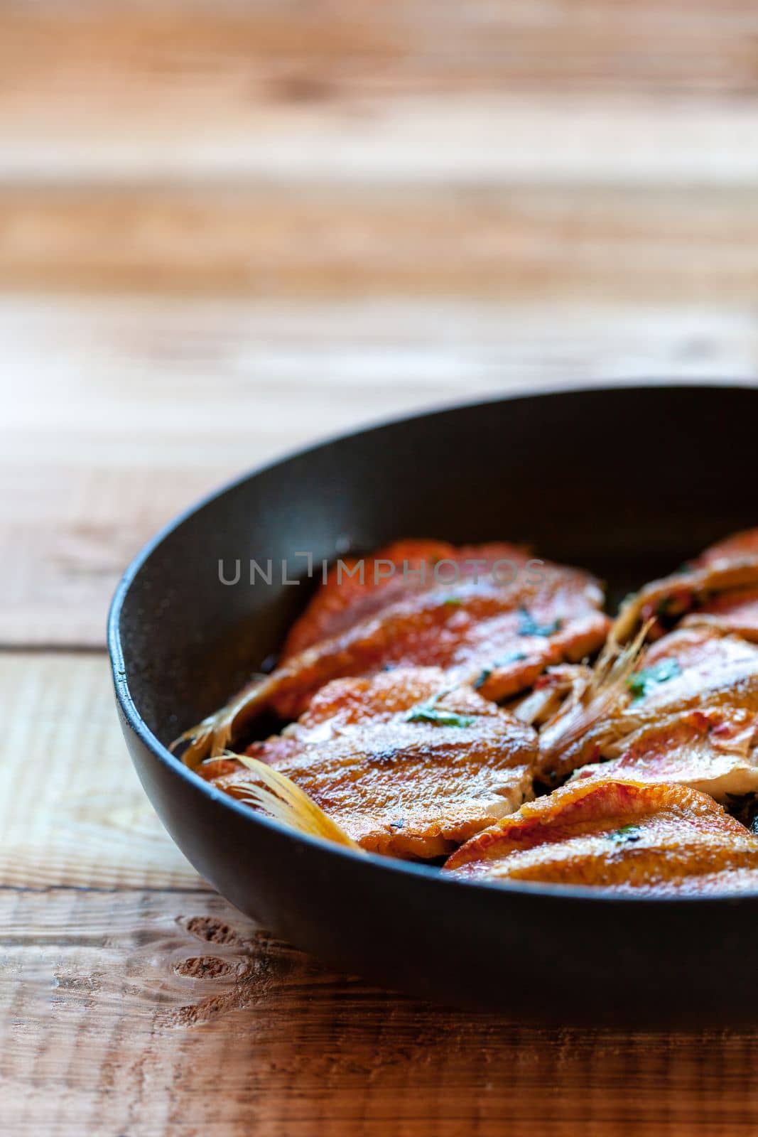 red mullet fish cooked on a pan, side view, selective focus, vertical photo, copyspace