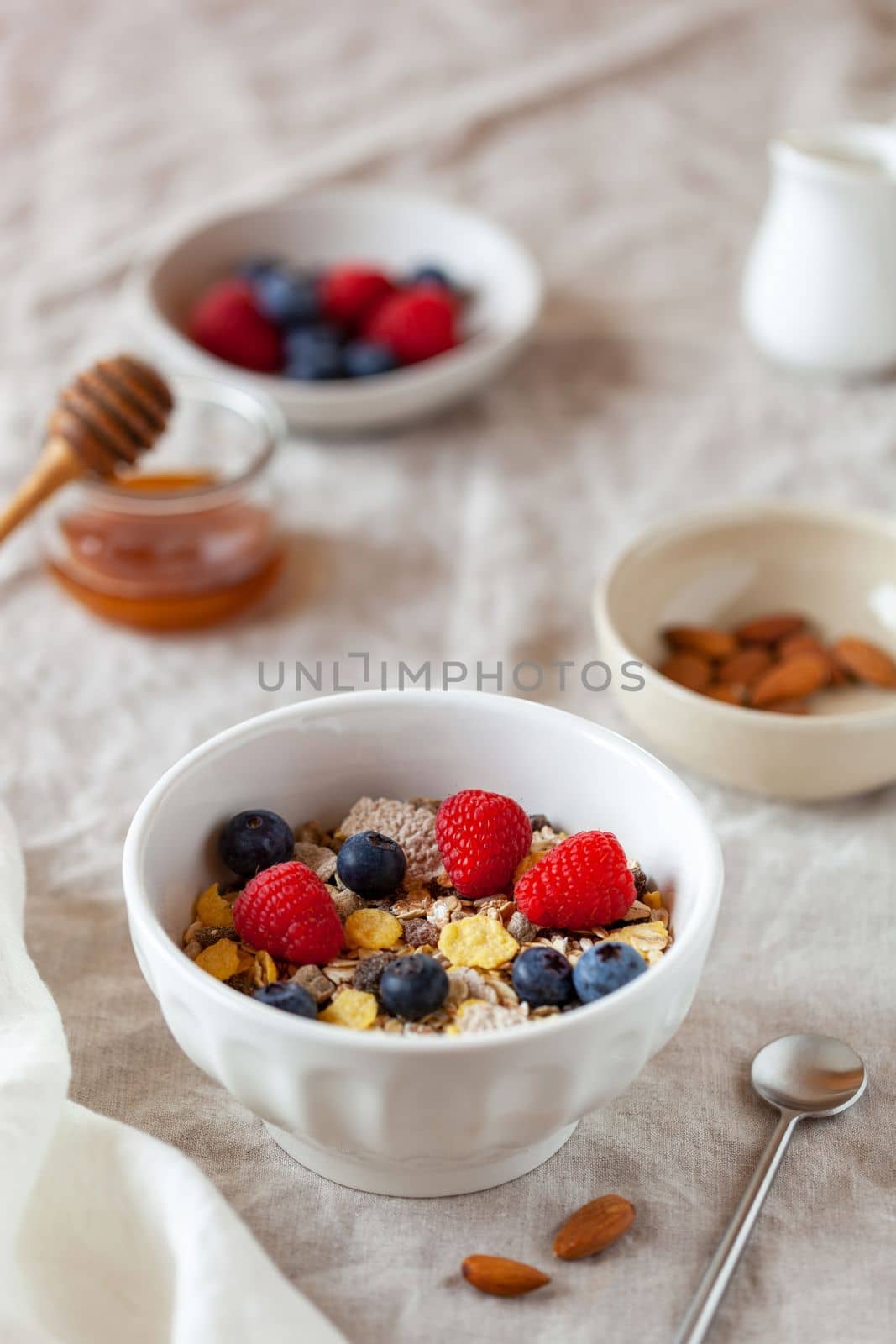 oat flakes breakfast portion with raspberries, blueberries and honey, on the table cloth