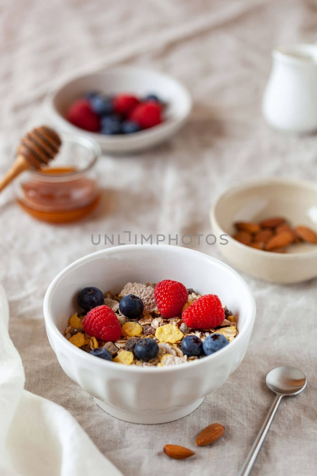 oat flakes breakfast portion with raspberries, blueberries and honey, on the table cloth