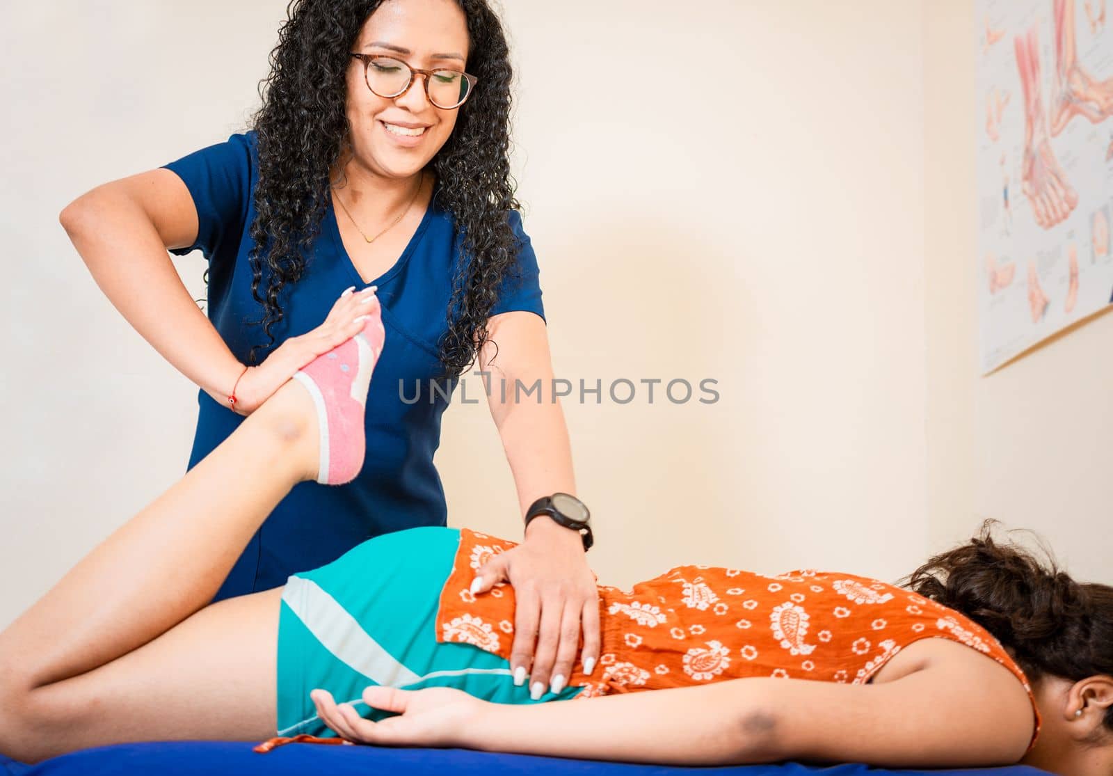Physiotherapist woman assisting knee to lying patient. Knee flexion physiotherapy to female patient, Chiropractor stretching knee to lying female patient