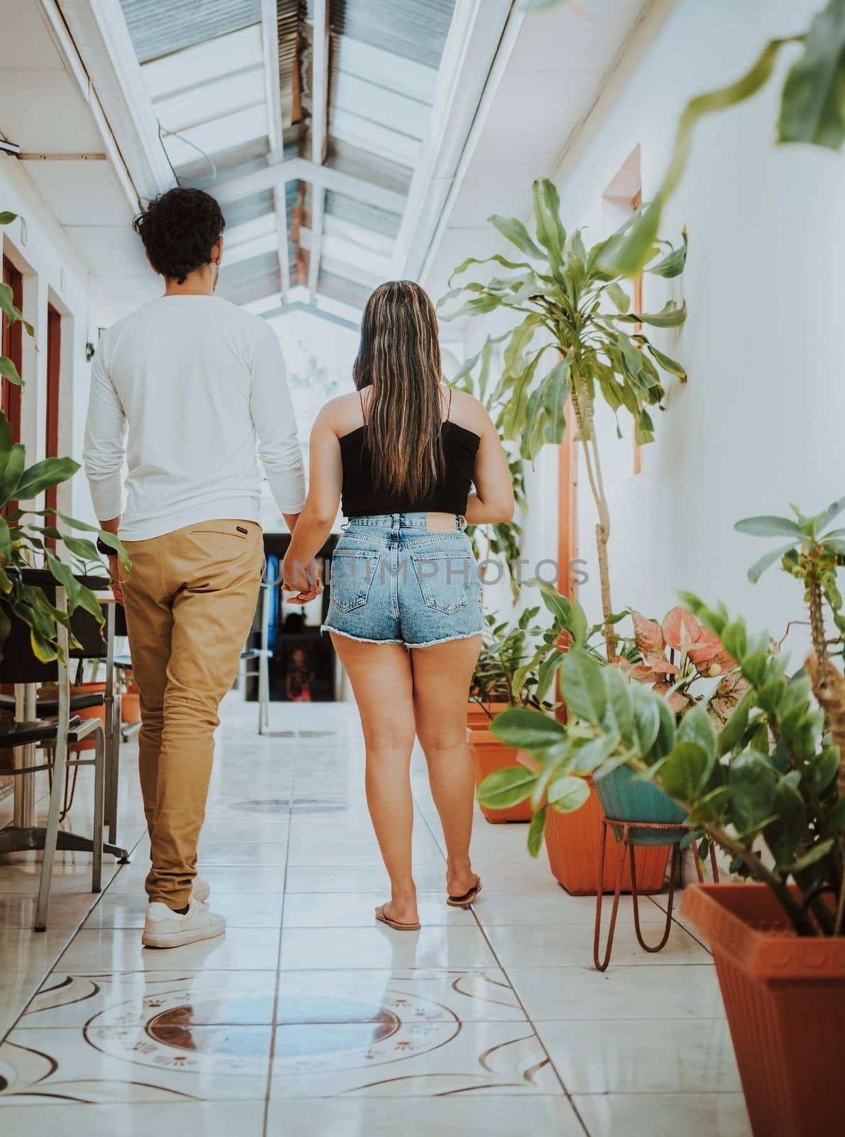 Young couple walking in corridor of tropical hotel. Smiling happy couple walking in hotel corridor. by isaiphoto