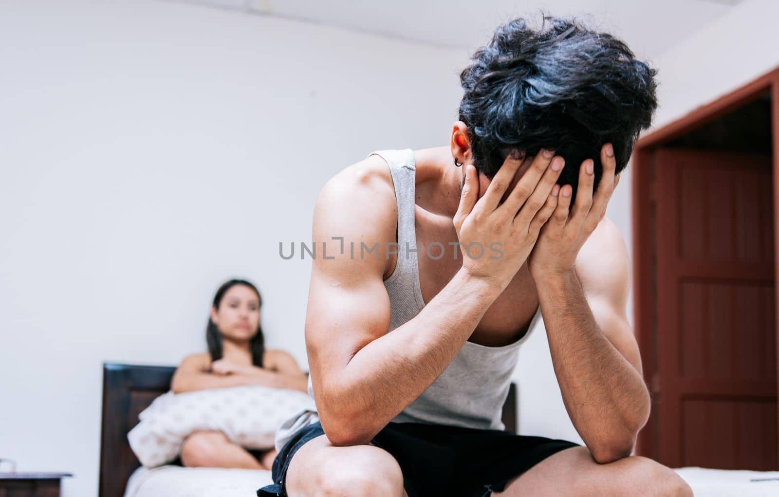 Worried man in bed with erectile dysfunction. Concept of crisis and couple problems in bed, Worried man sitting on the side of the bed and angry wife