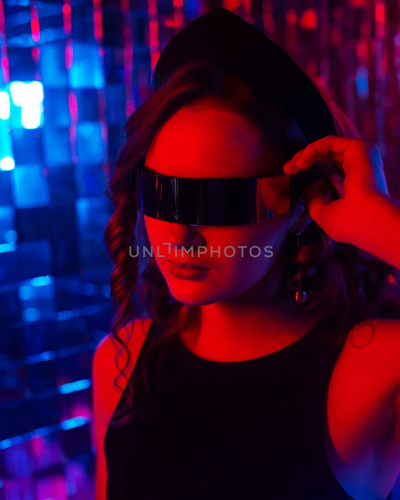 Close-up portrait of a caucasian woman in sunglasses in neon light against a mirror wall