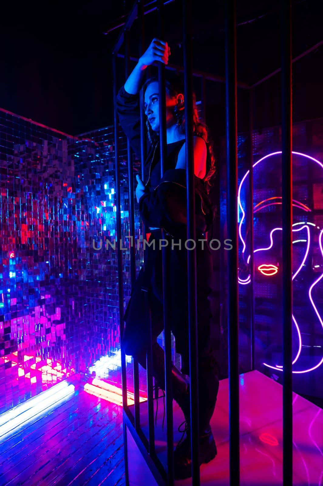 Caucasian woman in neon studio behind steel bars. by mrwed54