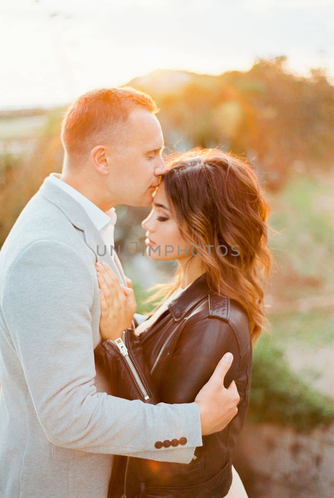 Groom kisses bride on the forehead, hugging her shoulders. High quality photo