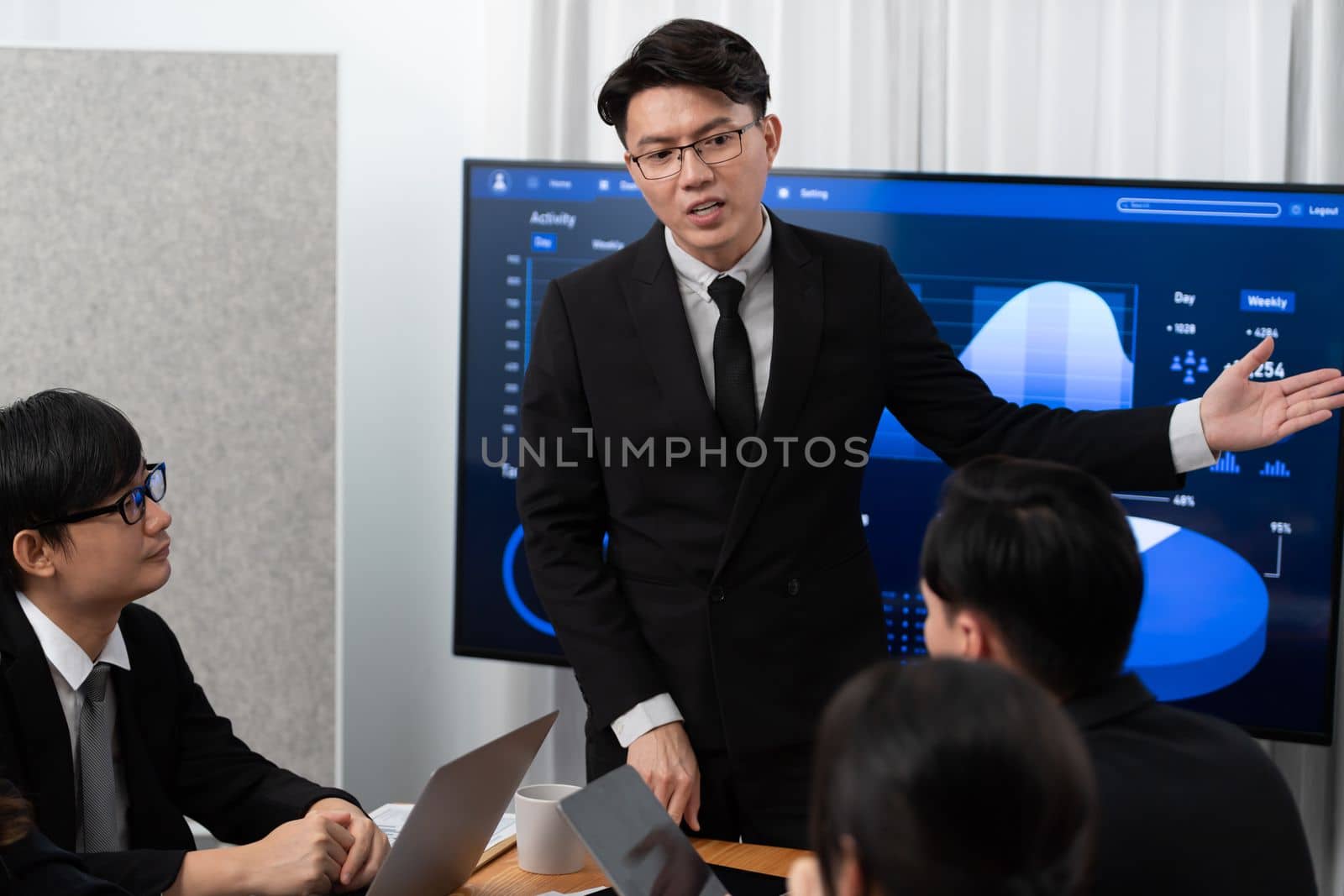 Confidence and asian businessman give presentation on financial analyzed by business intelligence in dashboard report to other people in board room meeting to promote harmony in workplace.