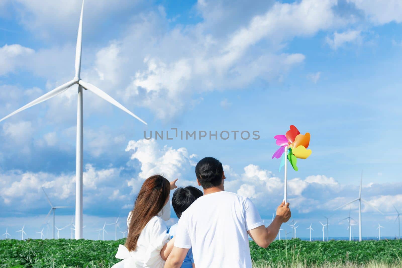 Concept of progressive happy family enjoying their time at the wind turbine farm by biancoblue