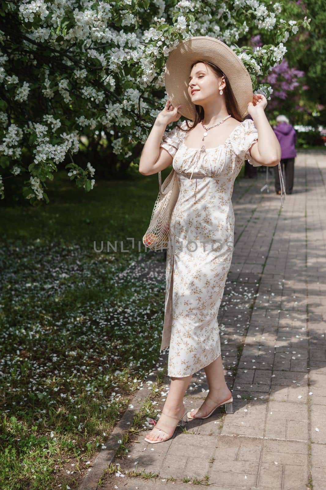 An attractive long-haired woman walks in the spring in the park of blooming apple trees. Spring portrait of a woman