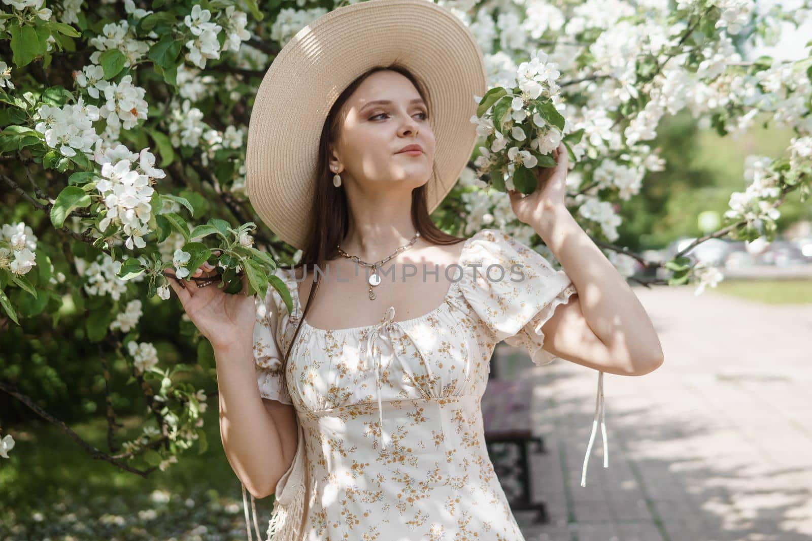 An attractive long-haired woman walks in the spring in the park of blooming apple trees. Spring portrait of a woman