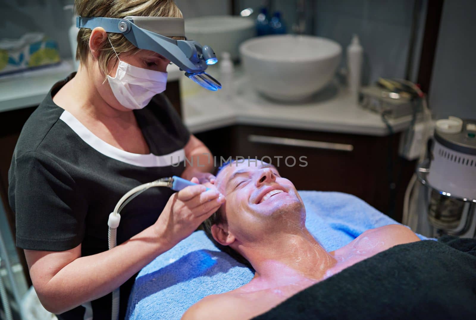 Modern beauty treatments for a younger-looking you. a man getting a non-invasive face lift at a beauty clinic. by YuriArcurs