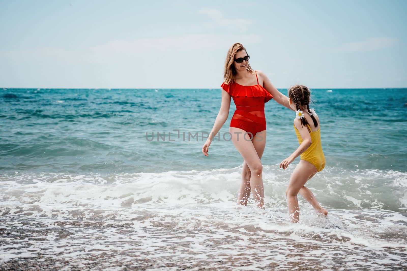 Happy loving family mother and daughter having fun together on the beach. Mum playing with her kid in holiday vacation next to the ocean - Family lifestyle and love concept by panophotograph