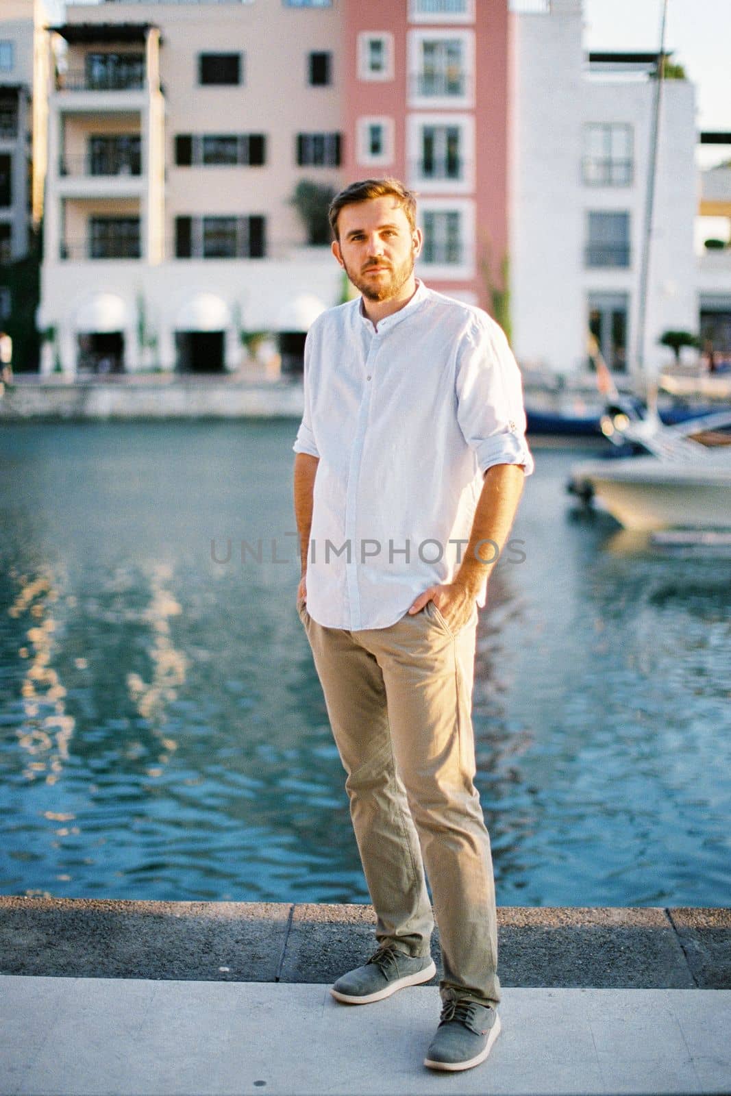 Young man with his hands in his pockets stands on the pier. High quality photo