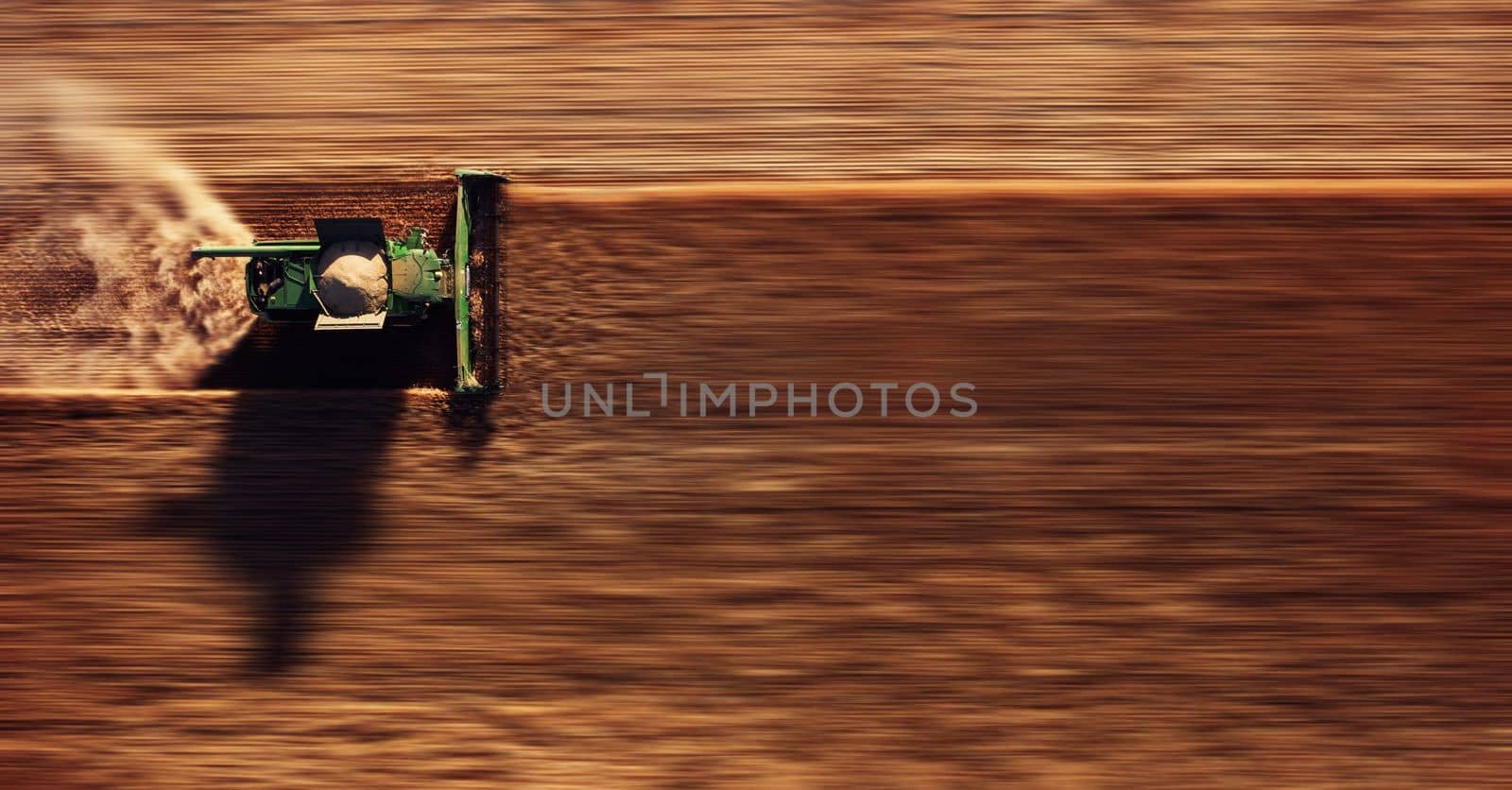 Harvester works in the field. Combine Harvesting Wheat, top view of a wheatfield. Field field of cereals during harvesting with background blurring.