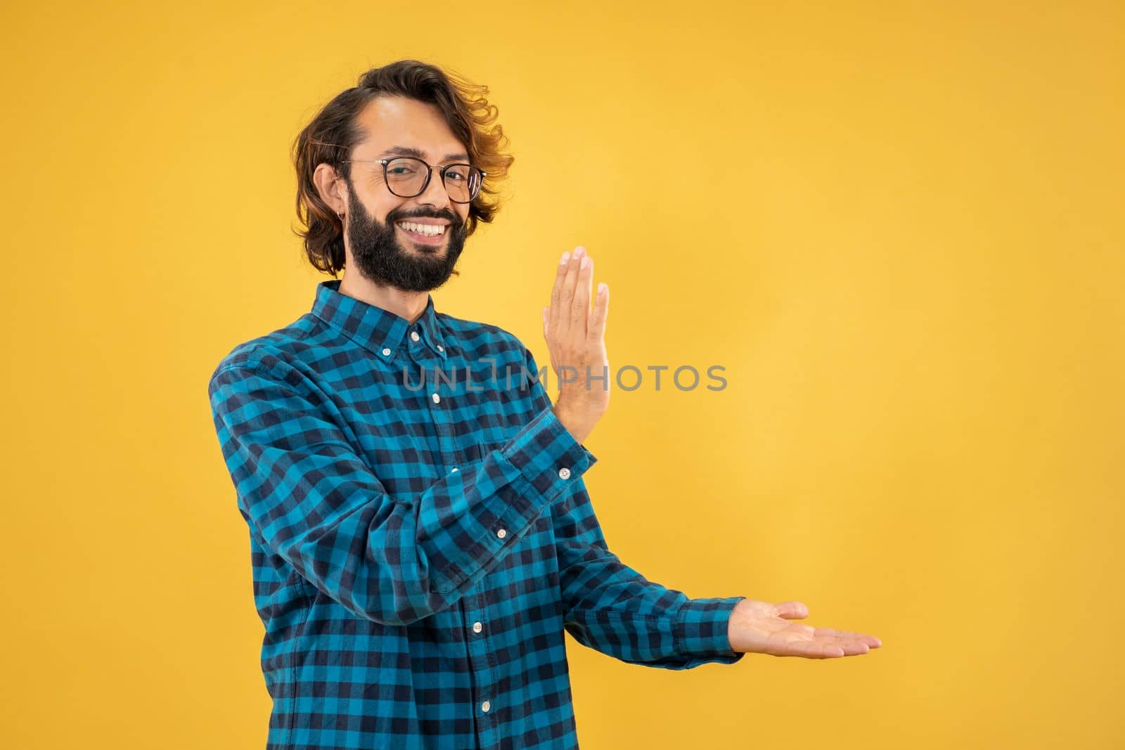 Young man standing over isolated yellow background pointing aside with hands open palms showing by PaulCarr