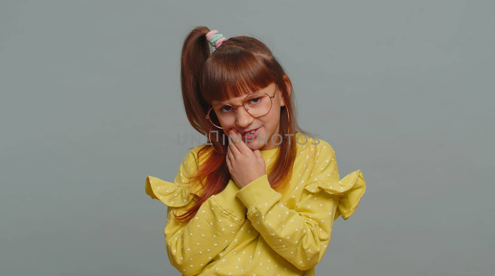 Dental problems. Young preteen child girl kid touching cheek, closing eyes with expression of terrible suffer from painful toothache, sensitive teeth, cavities. Toddler children on gray background