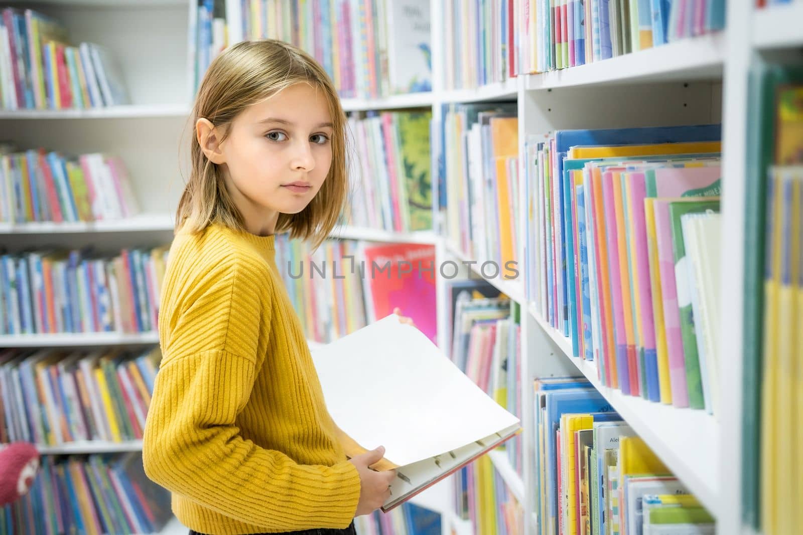 Schoolgirl choosing book in school library. Smart girl selecting literature for reading. Books on shelves in bookstore. Learning from books. School education. Benefits of everyday reading
