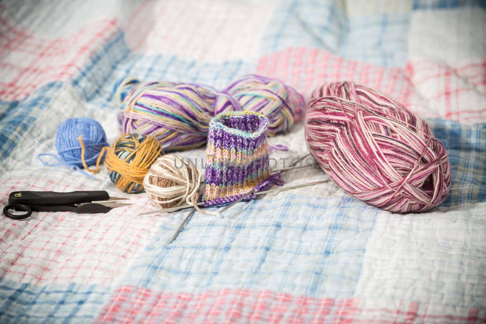 Colored threads, knitting needles and other items for hand knitting, on the bed .