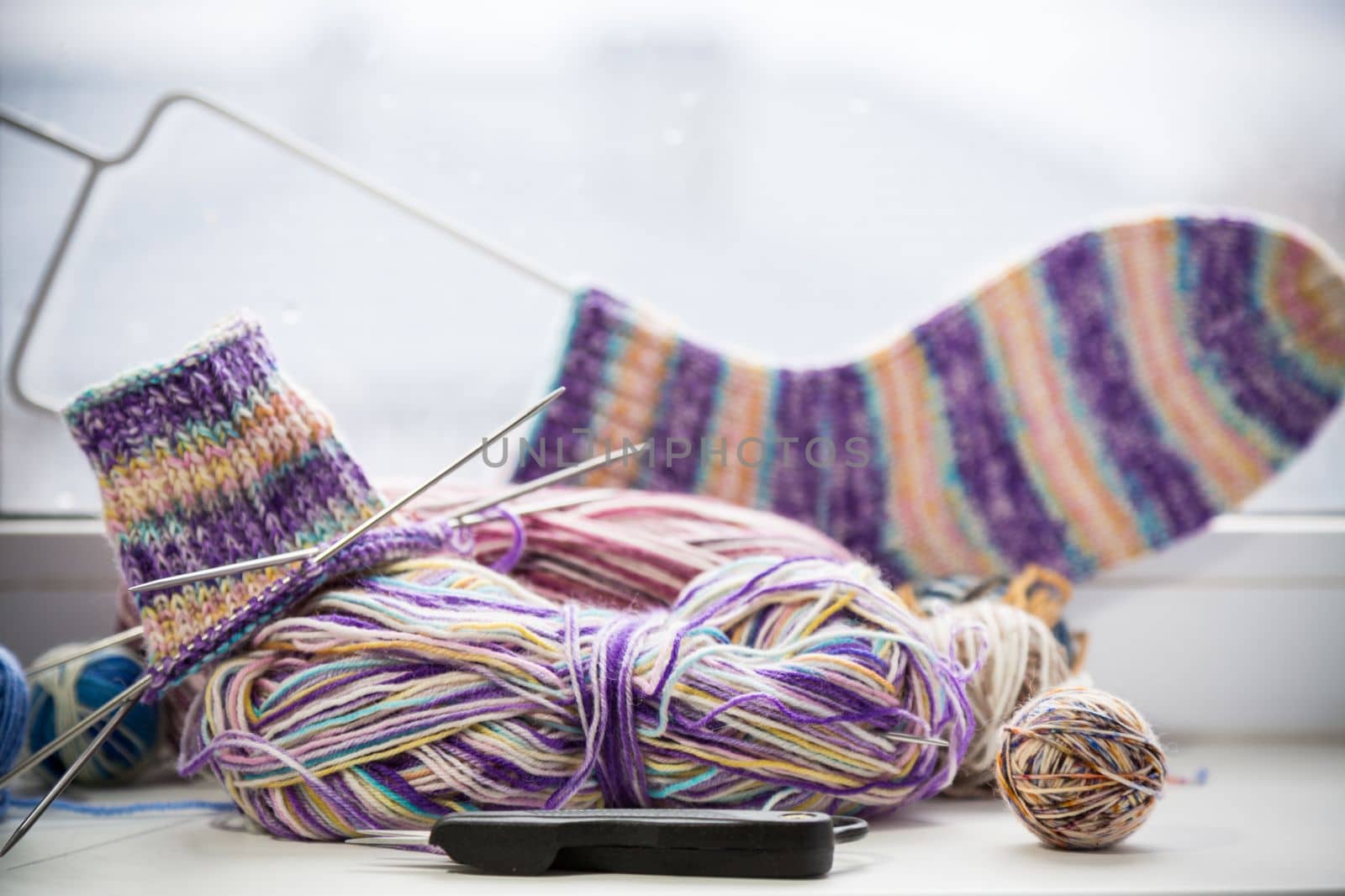 Colored threads, knitting needles and other items for hand knitting, on the windowsill .