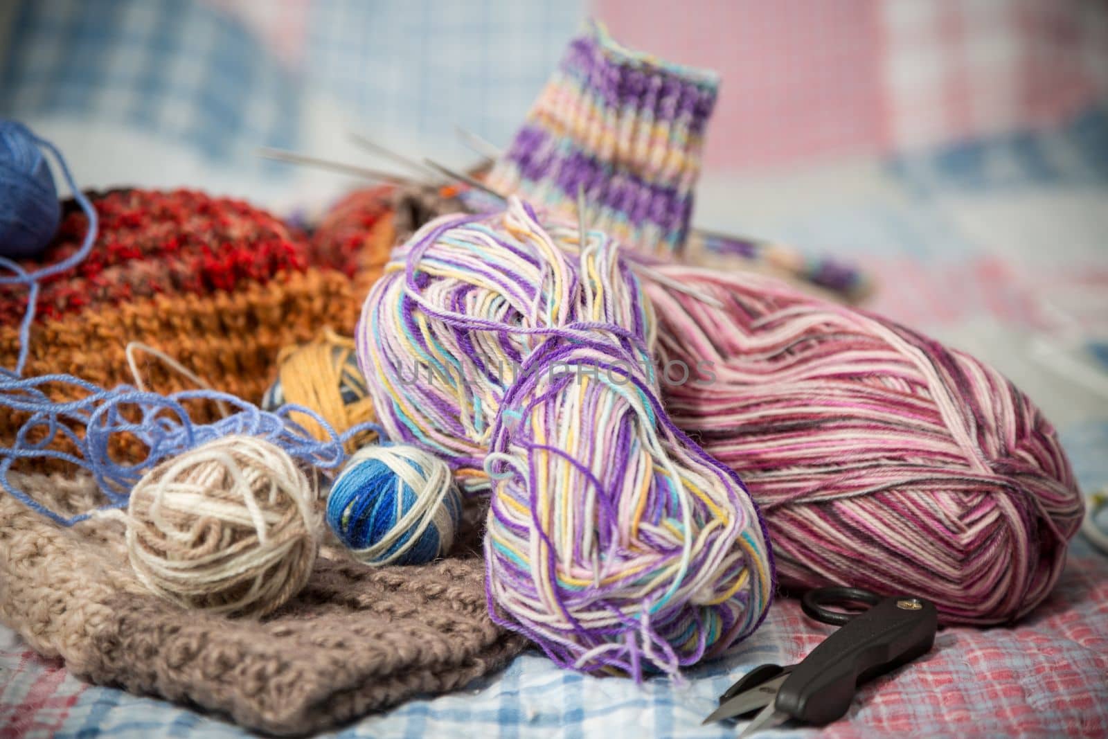 Colored threads, knitting needles and other items for hand knitting, on the bed .