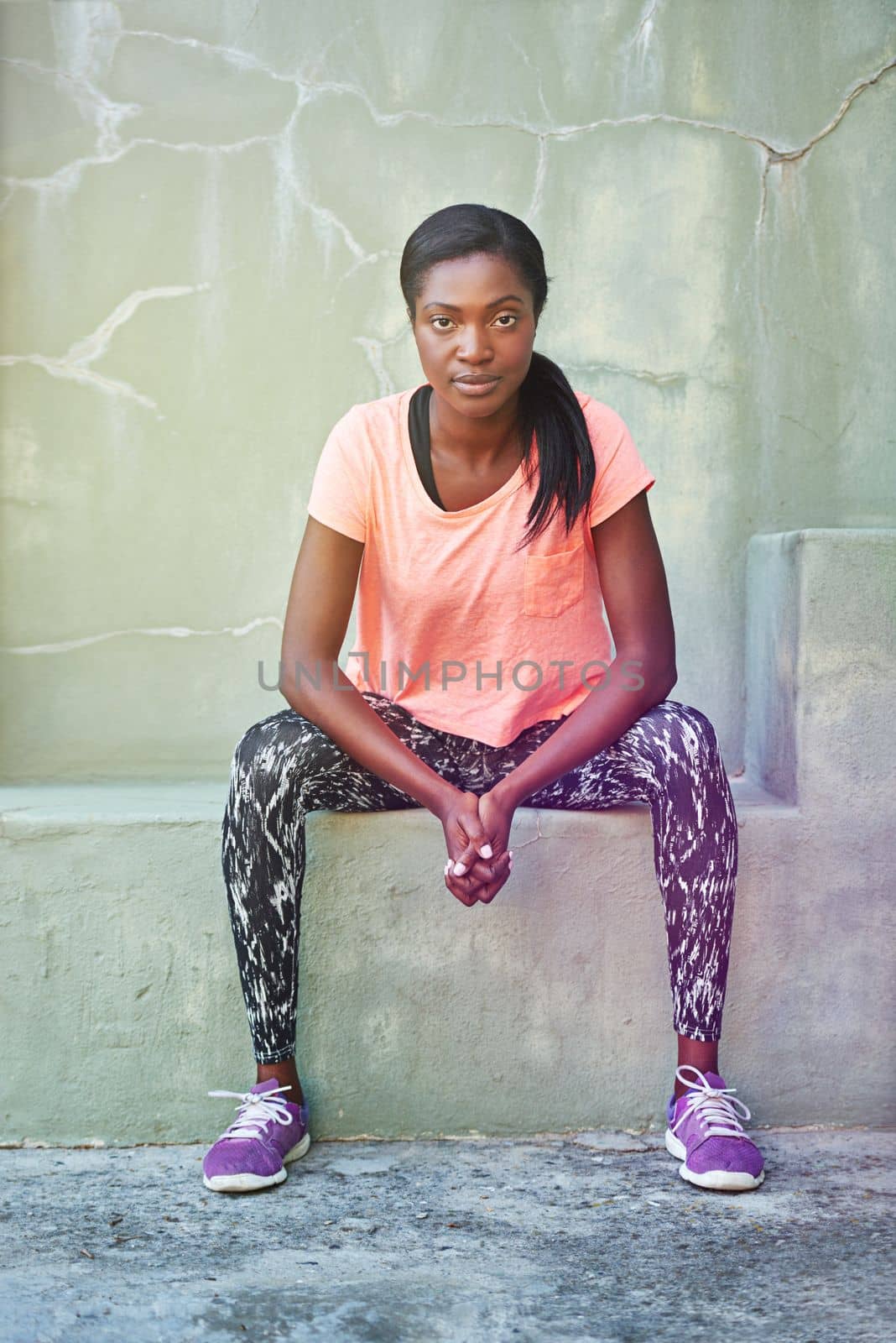 Ready for a workout. Portrait of an attractive and sporty young woman sitting outdoors. by YuriArcurs