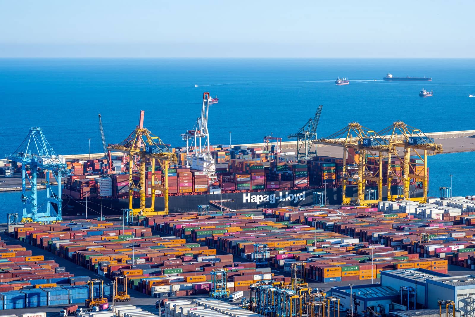 BARCELONA, SPAIN - January 31, 2023: The commercial harbour of Barcelona with a container ship, cranes and storage tanks
