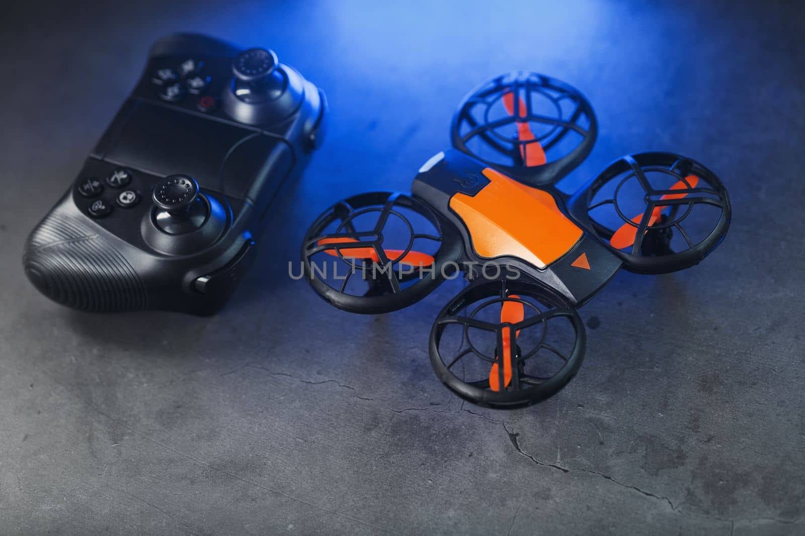 A reconnaissance quadcopter drone with an orange body and blue LED backlight on a dark background