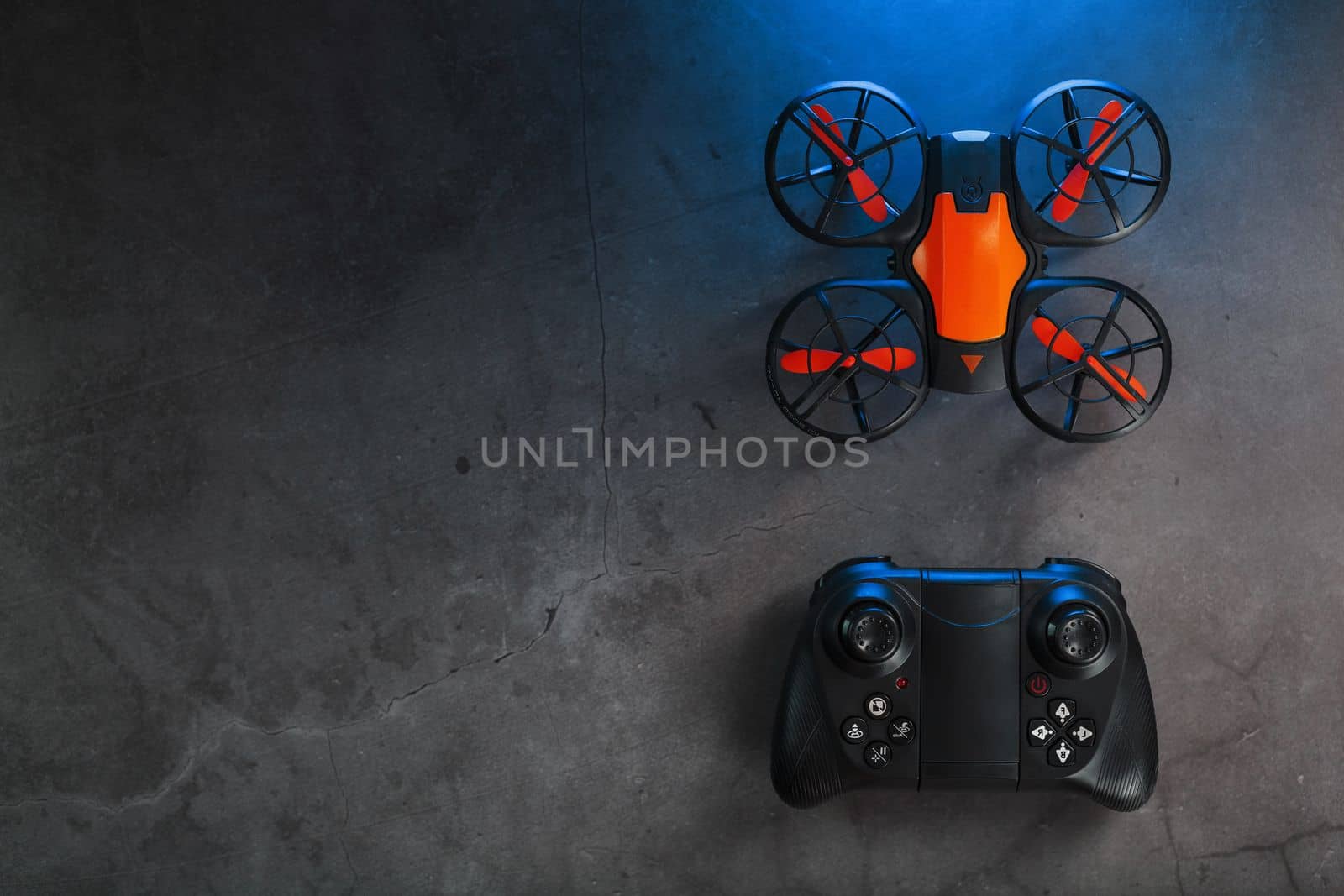 A reconnaissance quadcopter drone with an orange body and blue LED backlight on a dark background