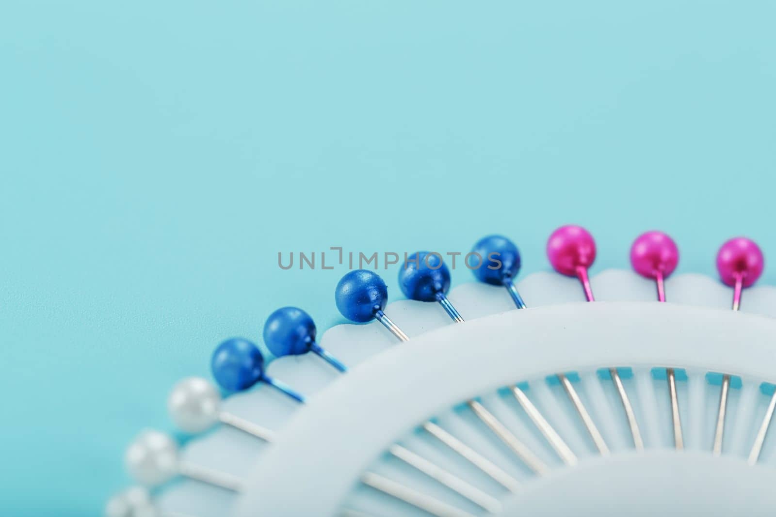 Sewing mother-of-pearl pins in a round white package on a blue background with free space