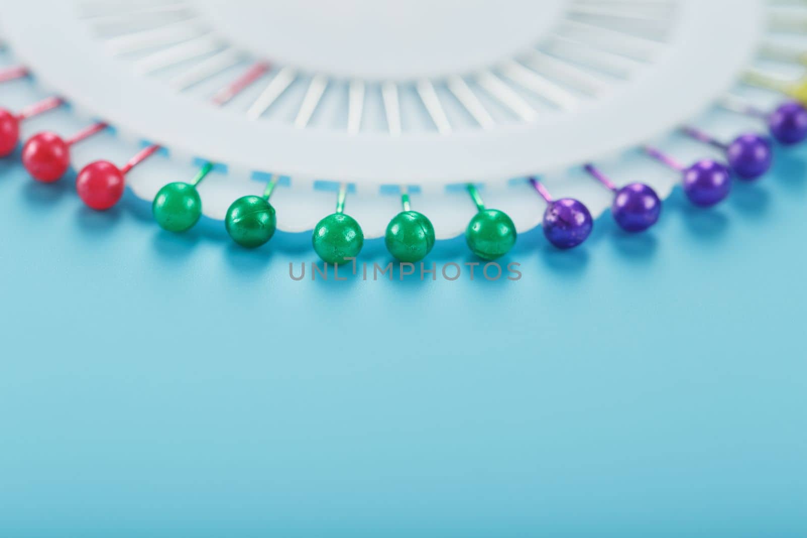 Sewing mother-of-pearl pins in a round white package on a blue background with free space