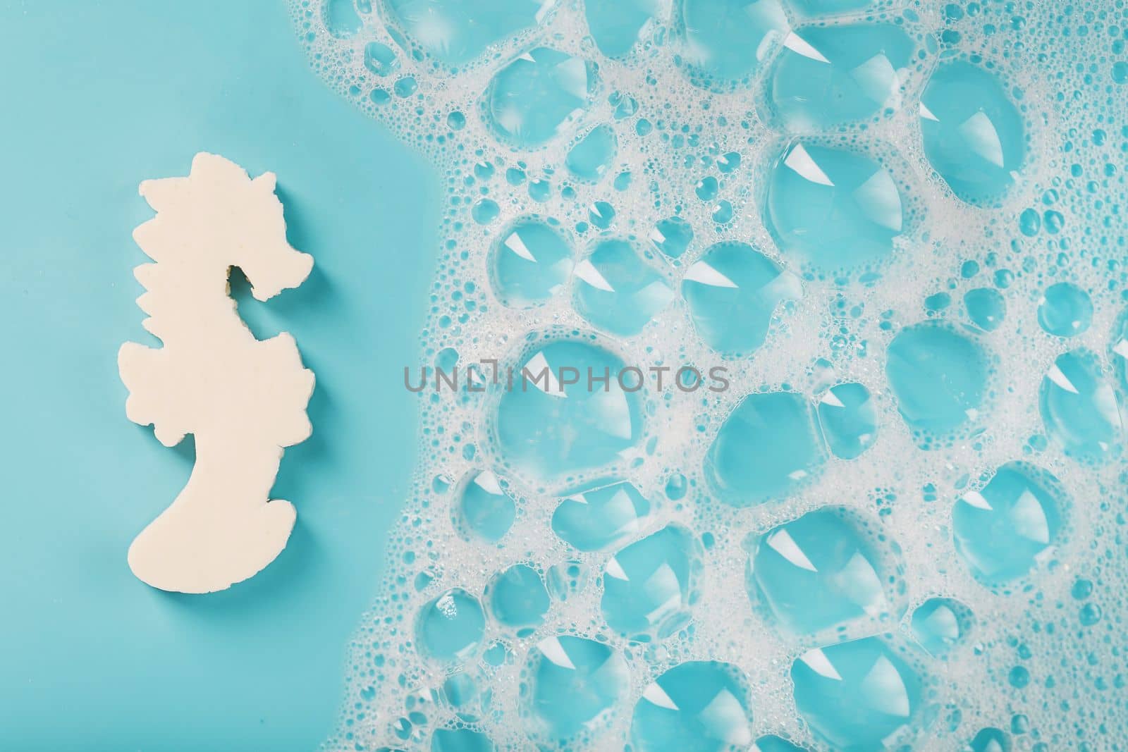 White soap in the shape of a seahorse with foam on a blue background