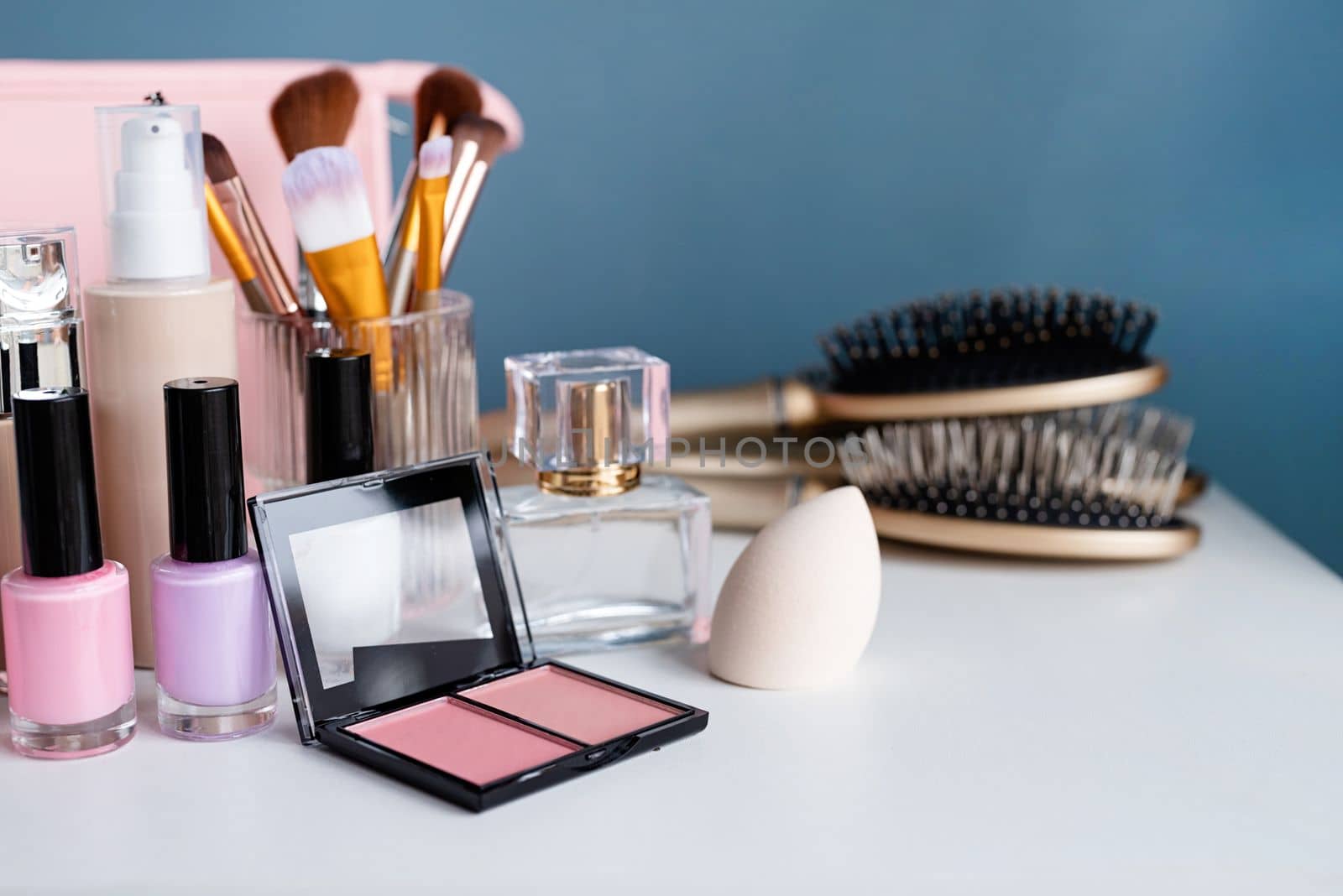 closeup of feminine cosmetic products standing on vanity table, nail polish and face powder