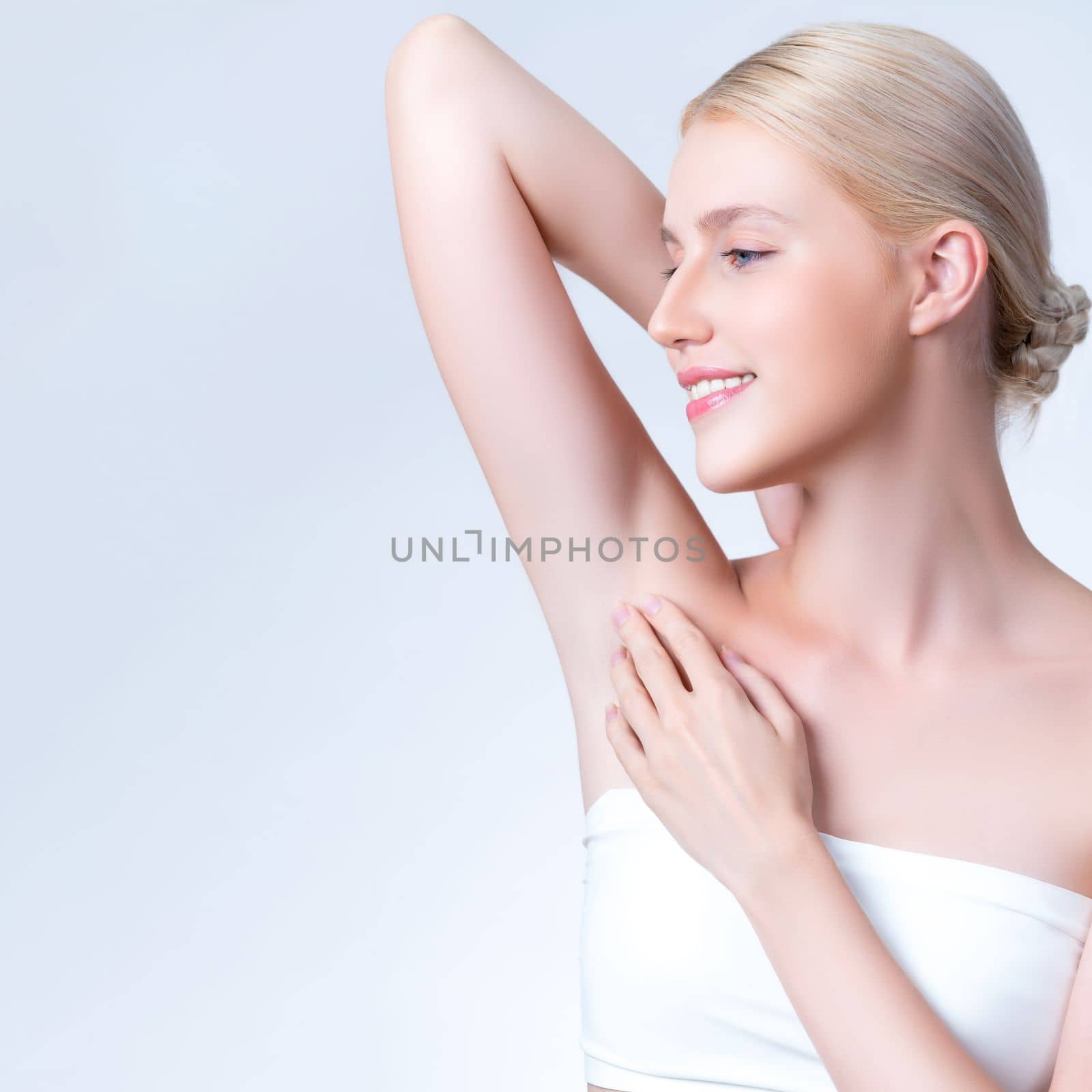 Closeup personable beautiful woman lifting her arm, showing her smooth clean skin and hairless underarm as beauty care concept of armpit laser hair removal and epilation in isolated background.