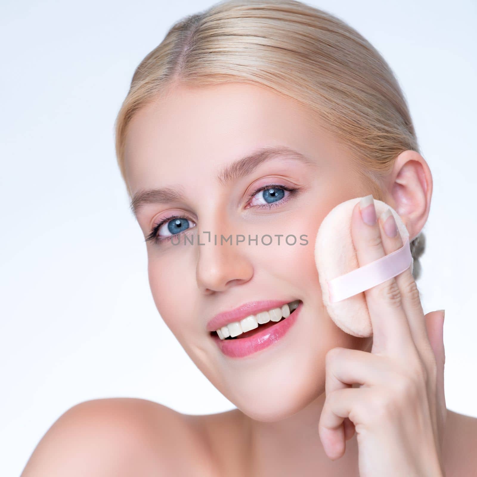 Closeup personable beautiful natural soft makeup woman using powder puff for facial makeup concept. Cushion foundation applying on young girl face in isolated background.