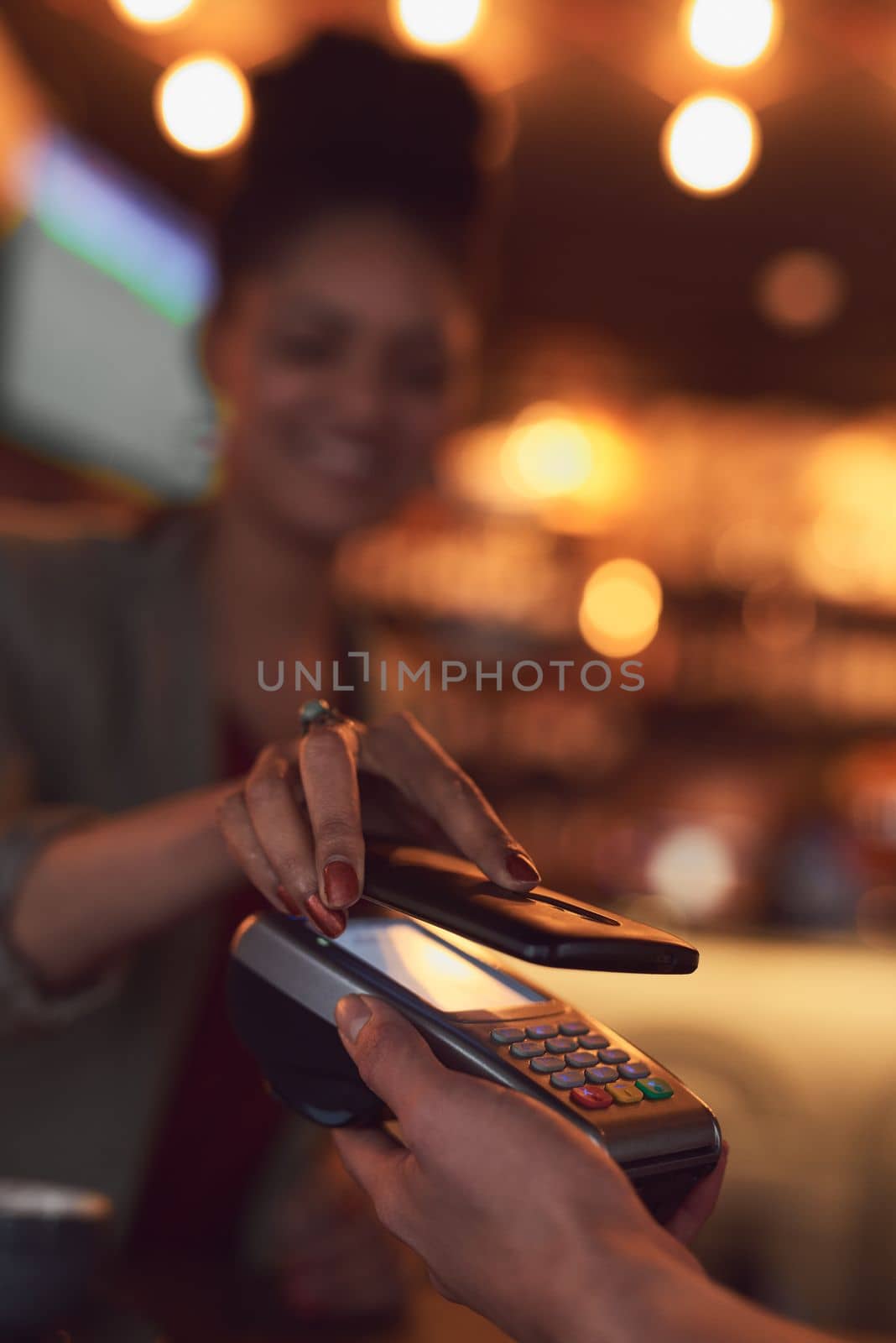 You never have to carry cash with you again. Closeup shot of a woman paying using NFC technology in a cafe. by YuriArcurs