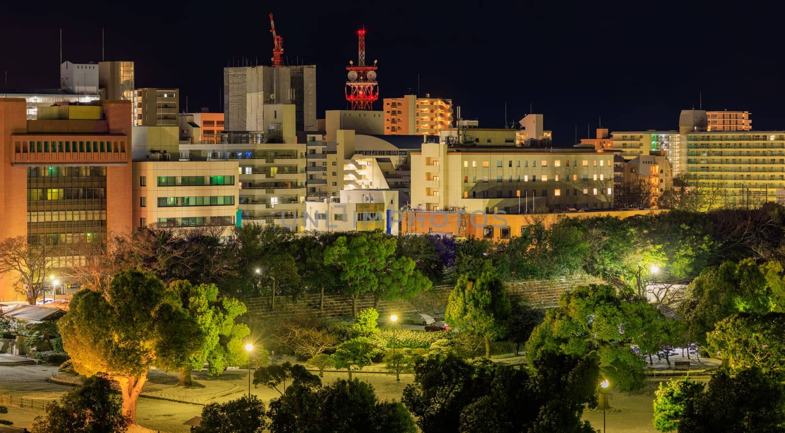 Lights from mid-rise offices and apartment buildings in small city at night by Osaze