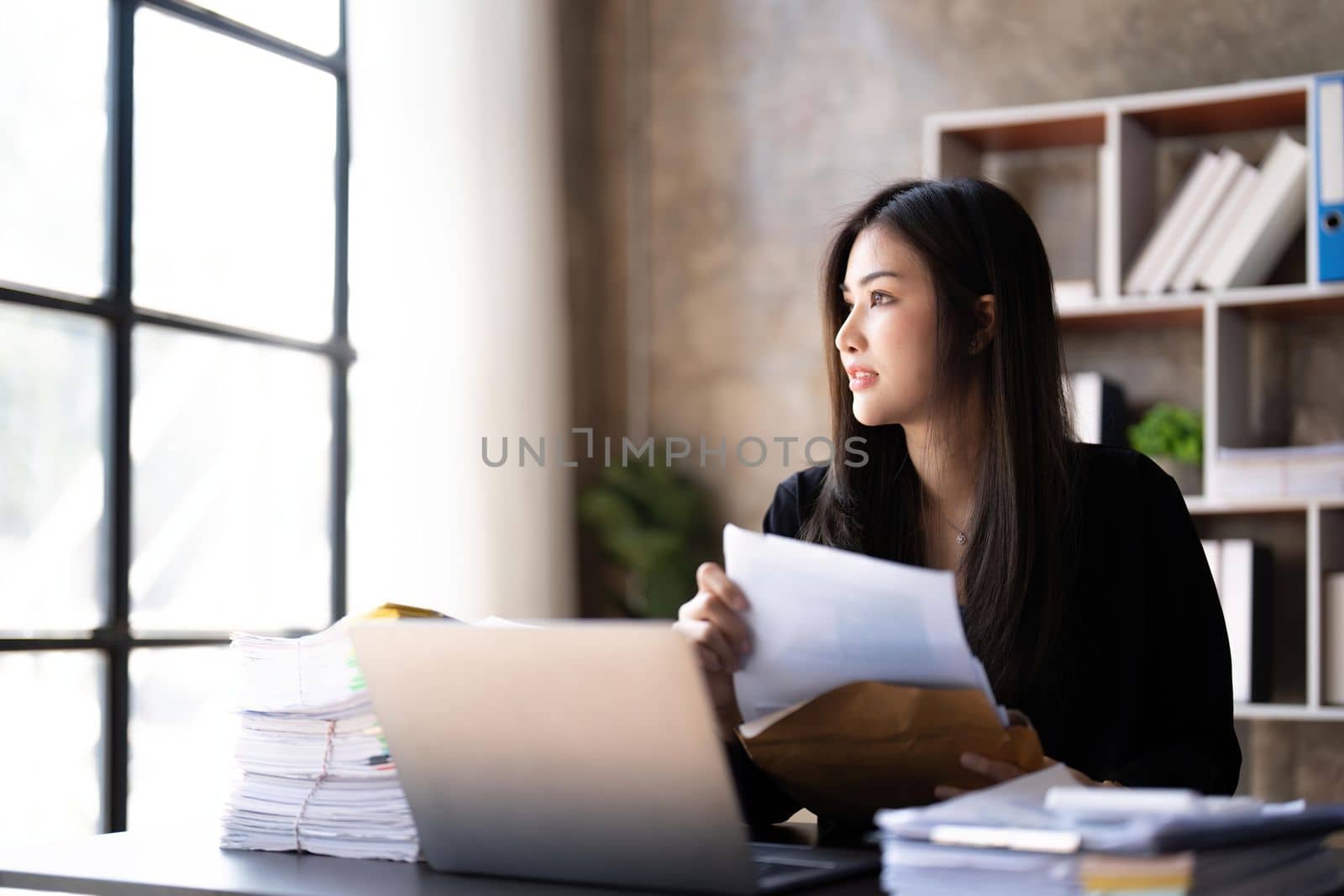 Young beautiful businesswoman working on laptop and in have documents on hand at bright modern office.